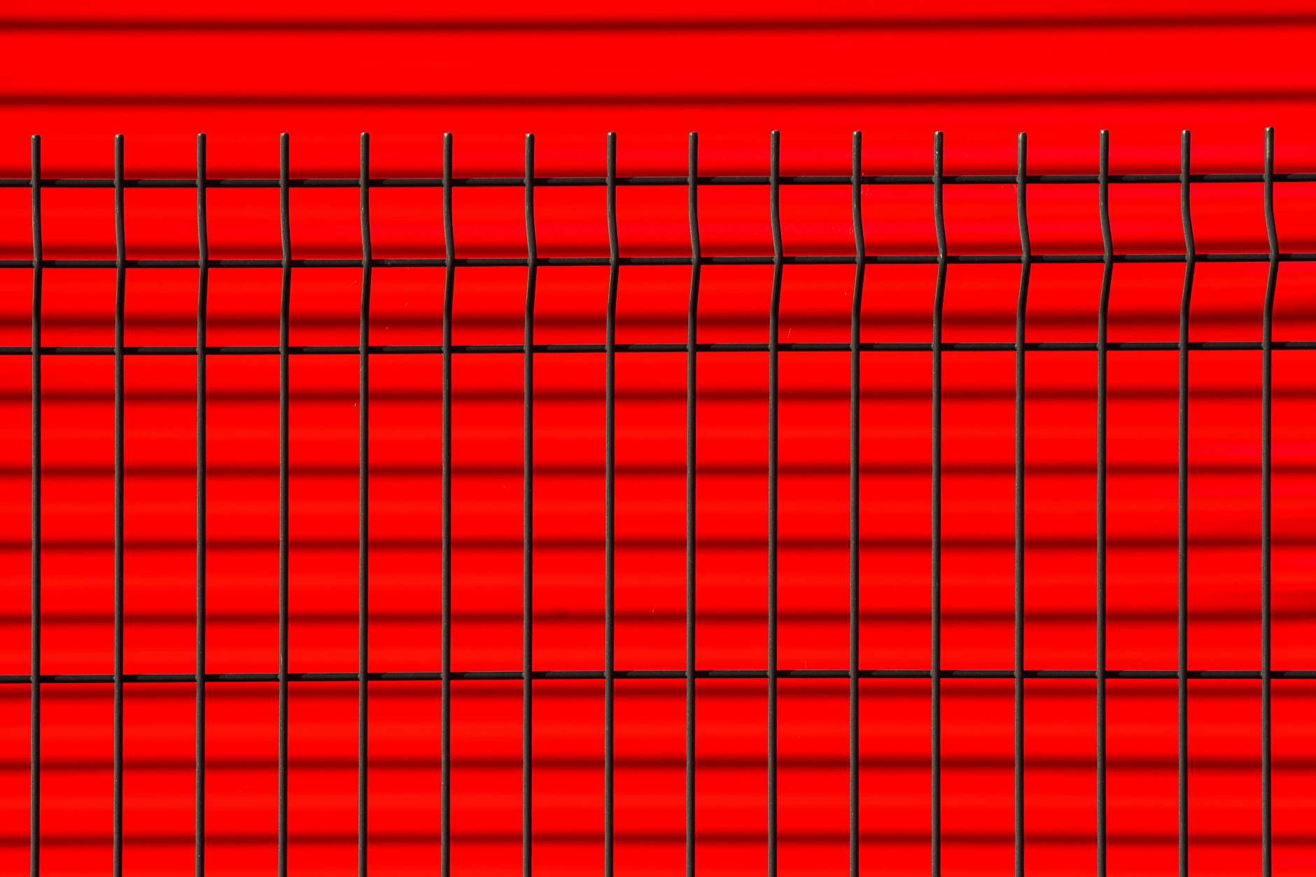 Zbliżenie czarnego metalowego ogrodzenia na tle czerwonej ściany