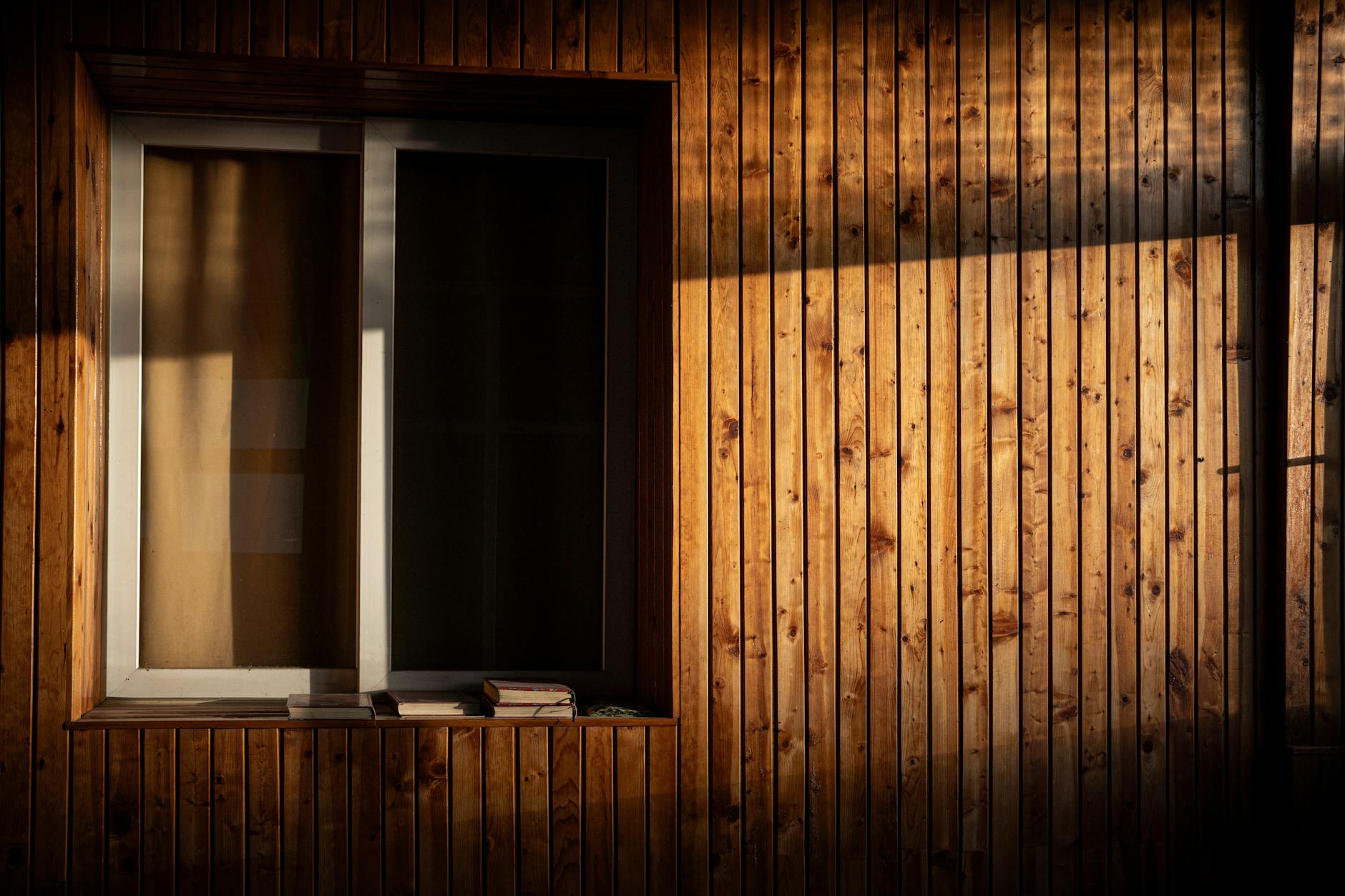 Drewniany parapet przy oknie z książkami w miękkim, naturalnym świetle