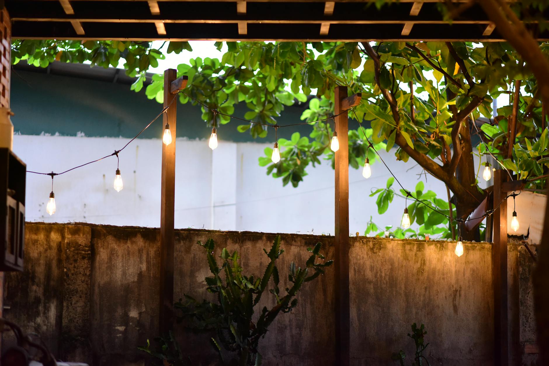 Przytulny taras ogrodowy z girlandami świetlnymi wśród zieleni