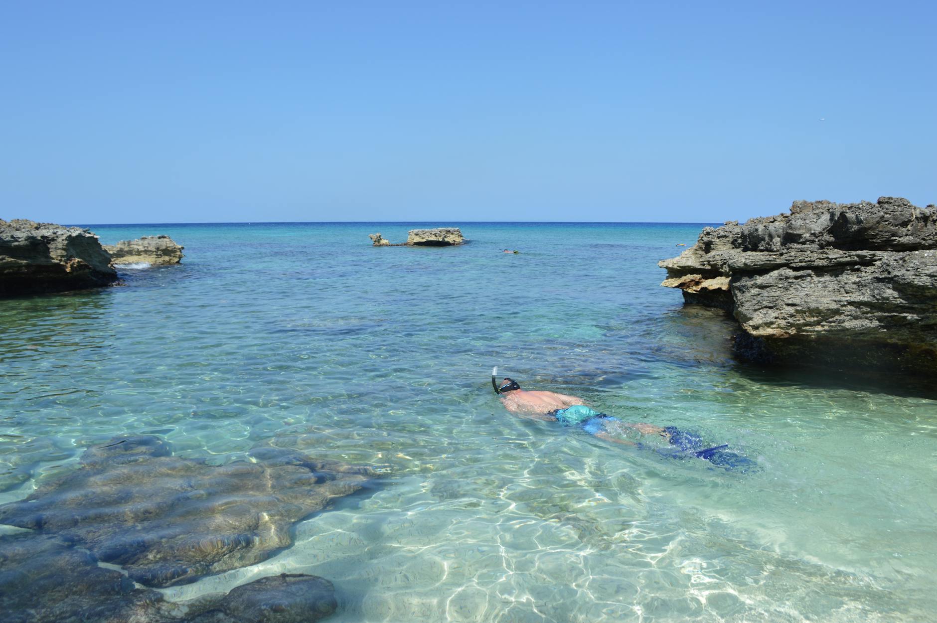 Snorkujący turysta w przejrzystej wodzie przy skalistym wybrzeżu Sharm El Sheikh